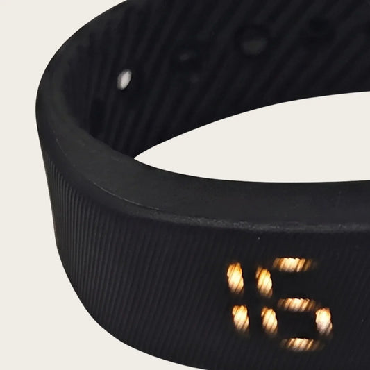 Close-up of the Sovune Nudge vibrating alarm wristband with its amber display lit