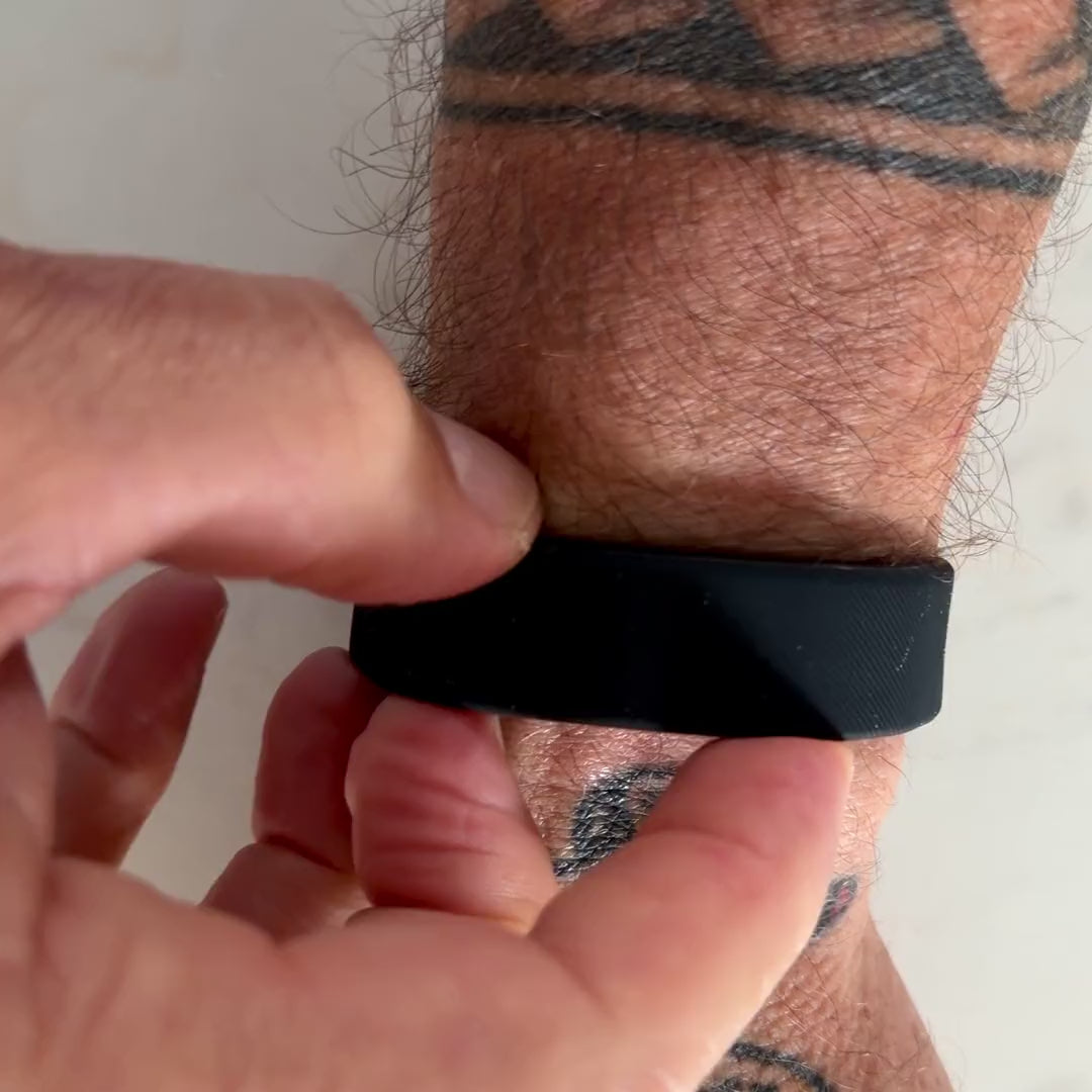 Close-up of a hand pressing the button on the Sovune Nudge band to light the display.